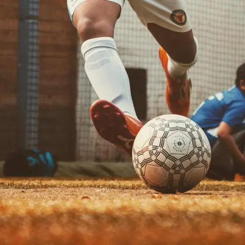 A man is kicking a football by foot